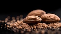 Fresh whole almonds on dark background with ground almond powder, macro food photography with selective focus and natural lighting.