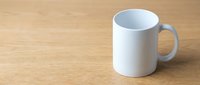 White ceramic mug on a wooden table, blank surface ready for custom print mockup design, copy space on left side.