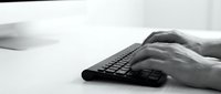 Professional hands typing on black keyboard in modern office workspace for business productivity and technology communication.