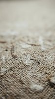 Natural burlap fabric texture with shallow depth of field showing woven jute fibers in neutral beige tones for rustic design backgrounds.