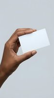 Male hand holding blank white business card mockup on gray background for branding and corporate identity design projects.