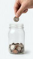 Hand dropping coin into glass jar filled with assorted coins, representing savings, financial planning, investment growth, and money accumulation for future goals.