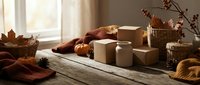 Cozy autumn still life with candles, pumpkins and fall leaves on rustic wooden table by window. Warm seasonal home decor for thanksgiving celebration.