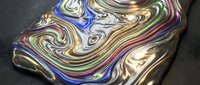 Colorful liquid metal surface with swirling rainbow patterns and reflective chrome finish on dark background for modern digital art and design projects.