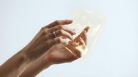 Hands holding glowing smartphone with bright light emanating from screen against white background for technology and communication concepts.