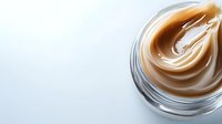 Creamy caramel swirl in glass jar on white background, smooth texture for dessert and confectionery designs, isolated product shot for commercial use.