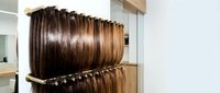 Professional hair extension samples displayed on salon rack showing various brown and blonde shades for color matching and selection in beauty industry.