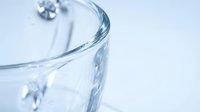 Clear glass tumbler with water droplets on clean white background for beverage photography and product design applications.