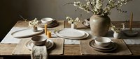 Elegant neutral table setting with ceramic dinnerware, wooden placemats and spring cherry blossoms for dining room decor and entertaining.