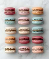 Colorful French macarons arranged in neat rows on marble background, featuring pastel pink, blue, white, orange and burgundy varieties filled with ganache.