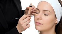 Professional eyebrow threading procedure at beauty salon with skilled technician shaping client brows using precise thread technique for hair removal.