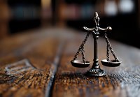 Decorative scales of justice on rustic wooden surface with shallow depth of field, symbolizing law, judgment, and legal balance in dramatic lighting.