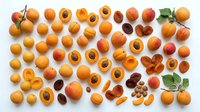 Apricots whole and halved with pits displayed on white background, suitable for food photography, culinary design, nutrition content, and recipe illustrations.