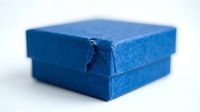 Blue gift box with damaged corner showing wear and tear on white background isolated for design projects and commercial use.