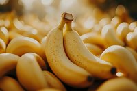 Ripe yellow bananas with brown spots standing out among a large pile of fresh fruit at market, selective focus with bokeh background.