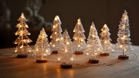 Illuminated miniature glass Christmas trees with warm fairy lights creating festive holiday atmosphere on wooden surface.