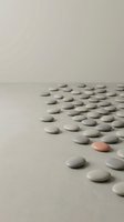 Smooth gray pebbles scattered on neutral surface with one distinctive coral pink stone standing out among collection for wellness and mindfulness concepts.