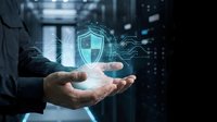 Businessman holding glowing shield icon with digital waves in server room environment, representing cybersecurity, data protection, and network security solutions for enterprises.