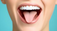 Close up view of healthy white teeth and pink tongue showing against turquoise background, demonstrating oral hygiene and dental care concept.