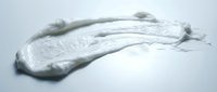 Thick white cosmetic cream or moisturizer smear isolated on light background, suitable for skincare product packaging and beauty advertising.