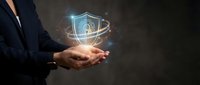 Businessman holding glowing digital shield with fingerprint security icon representing cybersecurity data protection and biometric authentication technology.
