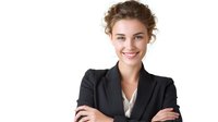 Young Caucasian businesswoman in black suit jacket and white blouse with natural makeup and updo hairstyle smiling confidently with arms crossed against white background.