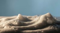 Sensual nude female torso with soft lighting creating intimate shadows and highlights on smooth skin against blue background for artistic photography.