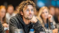Young caucasian man with curly hair listening attentively during business conference or seminar. Professional development and corporate training concept.