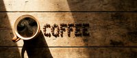 Steaming cup of black coffee on rustic wooden table with word Coffee spelled out in roasted beans, warm moody lighting.
