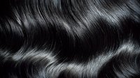 Close-up of glossy black wavy hair with natural shine and texture, showcasing healthy strands for beauty and haircare advertising.