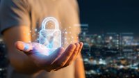 Businessman holding glowing digital padlock hologram with sparkling effects over cupped hands against blurred city lights background for cybersecurity concepts.