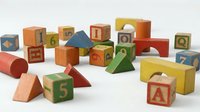 Colorful wooden educational toy blocks with letters and numbers scattered on white background for children learning and development activities.
