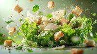 Flying ingredients of fresh Caesar salad with crispy croutons, romaine lettuce, parmesan cheese and herbs in green tones with water drops and motion blur.