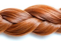 Twisted strand of shiny copper red hair braid on white background, showing smooth texture and natural highlights. Isolated element for beauty and hair care designs.