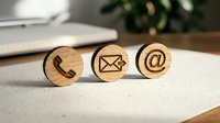 Wooden circular blocks with engraved contact icons including phone, envelope, and email symbol on white surface for communication and business networking concepts.