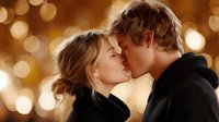 Young couple sharing intimate kiss with warm golden bokeh lights creating romantic atmosphere for Valentine's Day celebration and love concepts.
