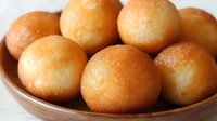 Golden fried dumplings in wooden bowl, traditional Asian sweet dessert balls with crispy exterior, homemade comfort food ready for serving.