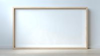 Empty wooden frame with white canvas on wooden surface against gray wall for mockup and presentation purposes.