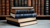 Stack of vintage hardcover books with blue and brown leather bindings on marble surface against classic library background with antique bookshelf.