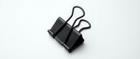 Black metal binder clip with wire handles isolated on white background for office supplies and document organization projects.