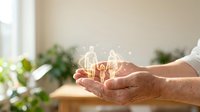 Hands holding glowing family silhouette symbol representing protection, care and unity in warm home environment for insurance and family concepts.