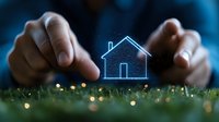 Glowing house icon between hands on grass with bokeh lights, representing real estate, home protection, property investment and smart home technology.