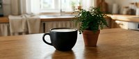 Black coffee cup and small potted plant on wooden table in bright modern kitchen interior with natural lighting for home decor and lifestyle concepts.
