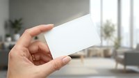 Hand holding blank white business card mockup in modern office interior with natural lighting for branding and corporate identity design projects.