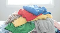 Colorful stack of folded casual clothing and garments on white surface in bright room ready for organization and storage.