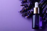 Lavender essential oil bottle with dropper and fresh purple lavender flowers on violet background for aromatherapy and natural skincare products.