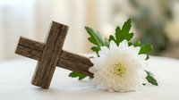 Wooden cross with white chrysanthemum flower on soft background for memorial, funeral, religious ceremony, Easter celebration, sympathy condolences.
