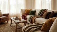 Cozy modern living room interior with neutral sofa, warm throw blankets, decorative pillows and natural lighting for home decor inspiration.