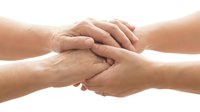 Caring hands of two people clasped together, symbolizing support, empathy, and compassion in healthcare or family relationships.
