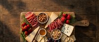 Gourmet charcuterie board with assorted meats, cheeses, nuts and fresh berries arranged on wooden cutting board for entertaining and holiday gatherings.